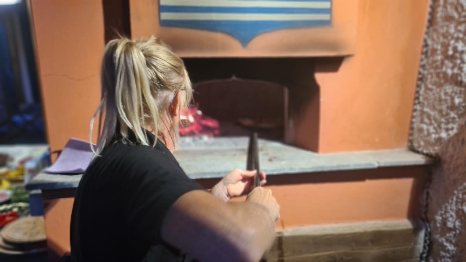 celine loading pizza into a pizza oven