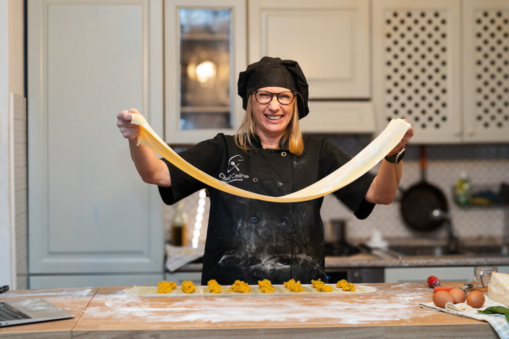 Chef Celine holding up a large sheet of pasta